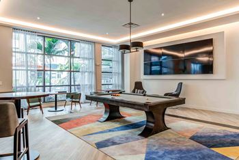 A room with a pool table and a television mounted on the wall.